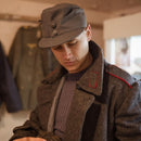 Man wearing a genuine Finnish army M65 field cap and vintage military wool coat indoors.