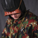 Man wearing genuine Italian army tanker goggles with blue lenses and camo uniform, head tilted downward