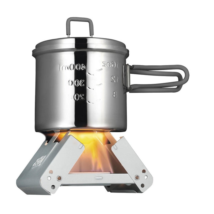 ESBIT klein opvouwbaar zakkooktoestel met vaste brandstof, dat een metalen pot met meetmarkeringen op een kampvuurvlam verwarmt