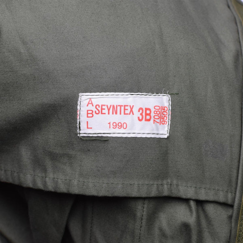 Close-up of white label sewn on olive green fabric of Belgian army field jacket M64 parka from 1990 size large