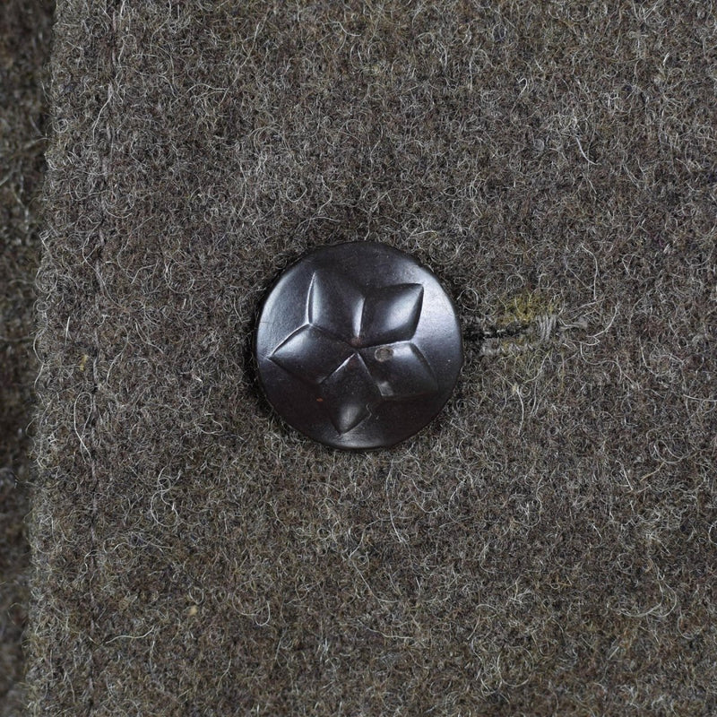 Close-up of a black star embossed button on grey-brown wool fabric from Bulgarian army jacket vintage military surplus.