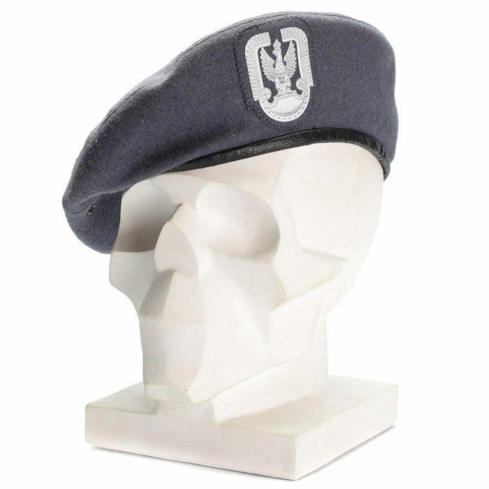 Grijze wollen Poolse militaire parachutistenbaret met badge aan de voorkant, weergegeven op het hoofd van een witte mannequin.