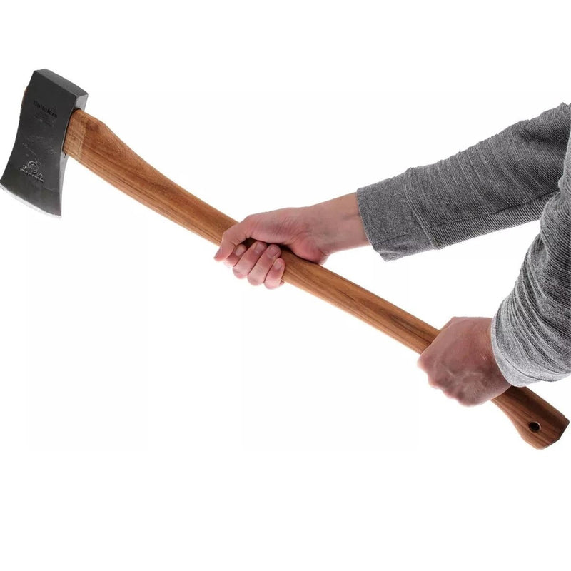 Person holding a HULTAFORS felling axe with carbon steel head and wooden handle against white background.