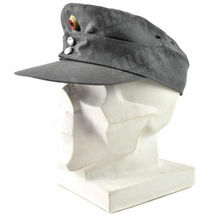 Originele bergpet van het Duitse leger in grijs met puntige voorkant en metalen insignes op het hoofd van een witte mannequin
