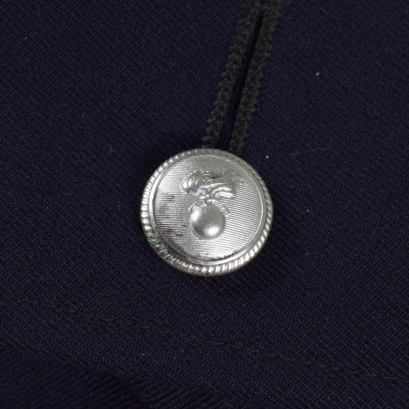 Close-up of silver-toned button with emblem on vintage Italian military police trench coat fabric.