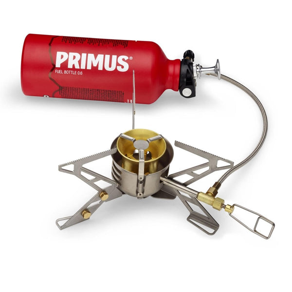 Primus OmniFuel II multifuel camping stove with red fuel bottle, stainless steel supports, and fuel hose for outdoor cooking.
