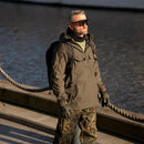 Man wearing SWISS EYE full frame tactical goggles with UV protection and camo pants standing by the water.