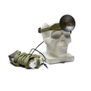 White sculpture with green straps and a black circular headlamp  on a white background